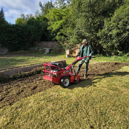 Jardinier Mes Jardiniers passant le motoculteur sur une pelouse à retourner