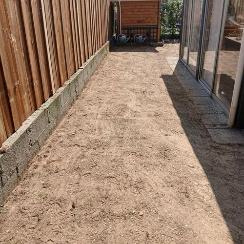 Sol ratissé et préparé après semis de pelouse le long d'une clôture en bois